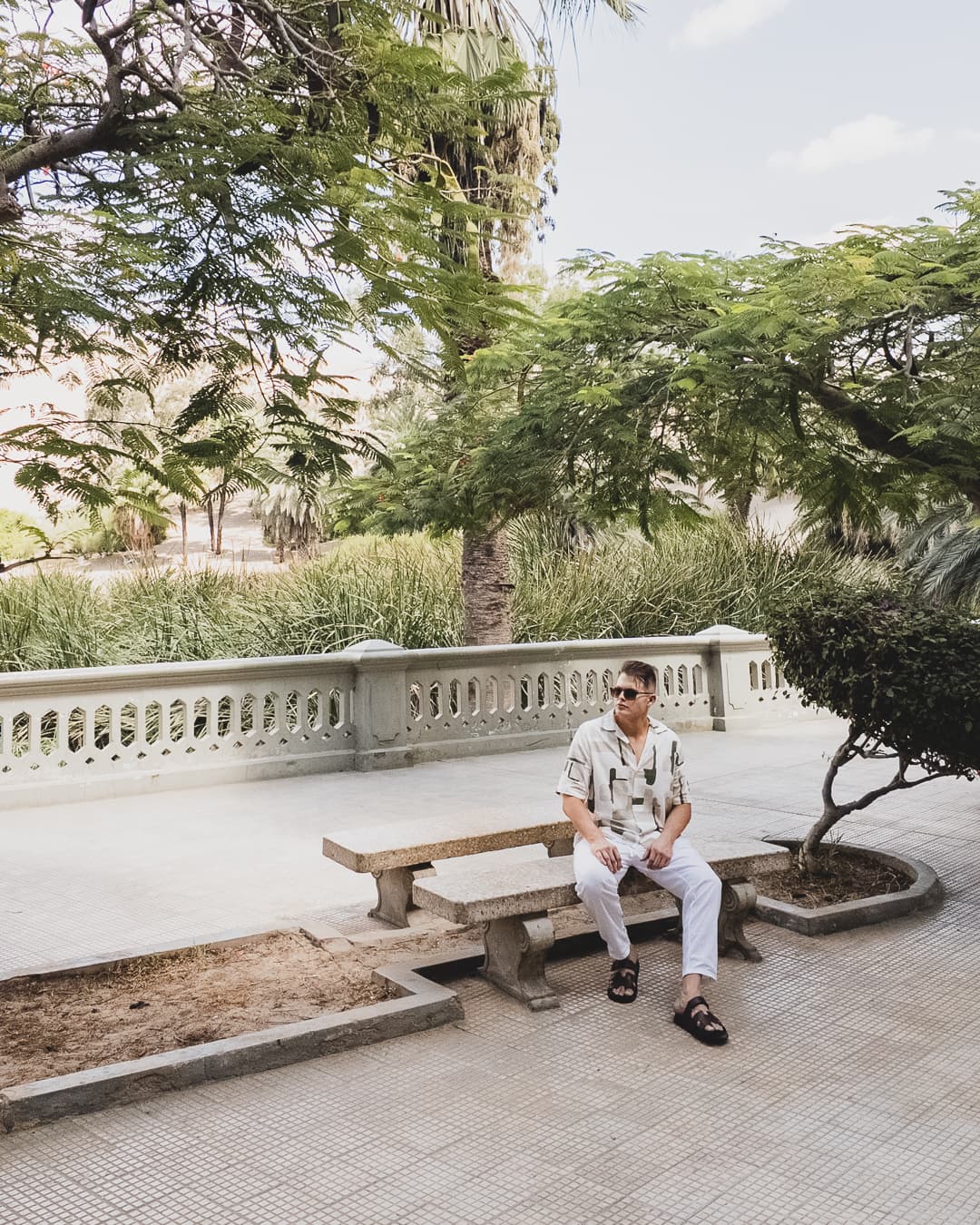 Alejandro sitting outdoors in a bright, calm setting surrounded by trees.