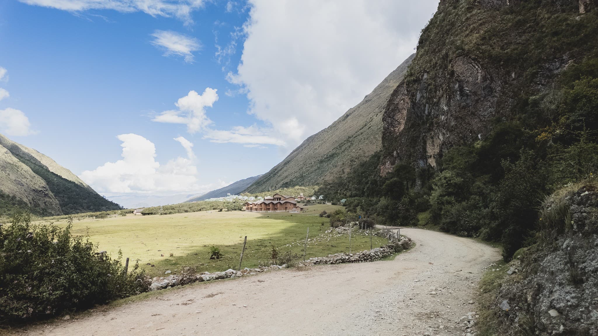 A mountain Andes valley road under a bright blue sky with clouds.