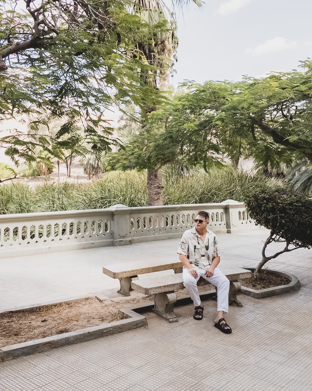 Alejandro Bermudez sitting on a bench in a tree-lined park.